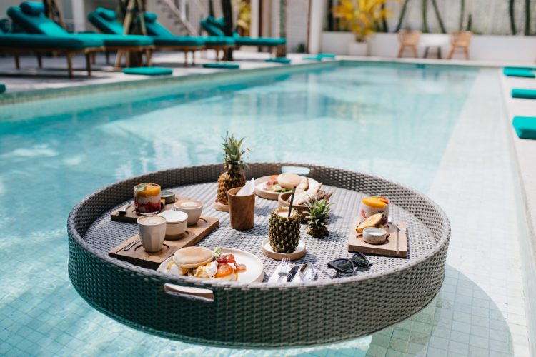 Picture of exotic lunch in hotel. Outdoor shot of table with fruits in swimming pool.